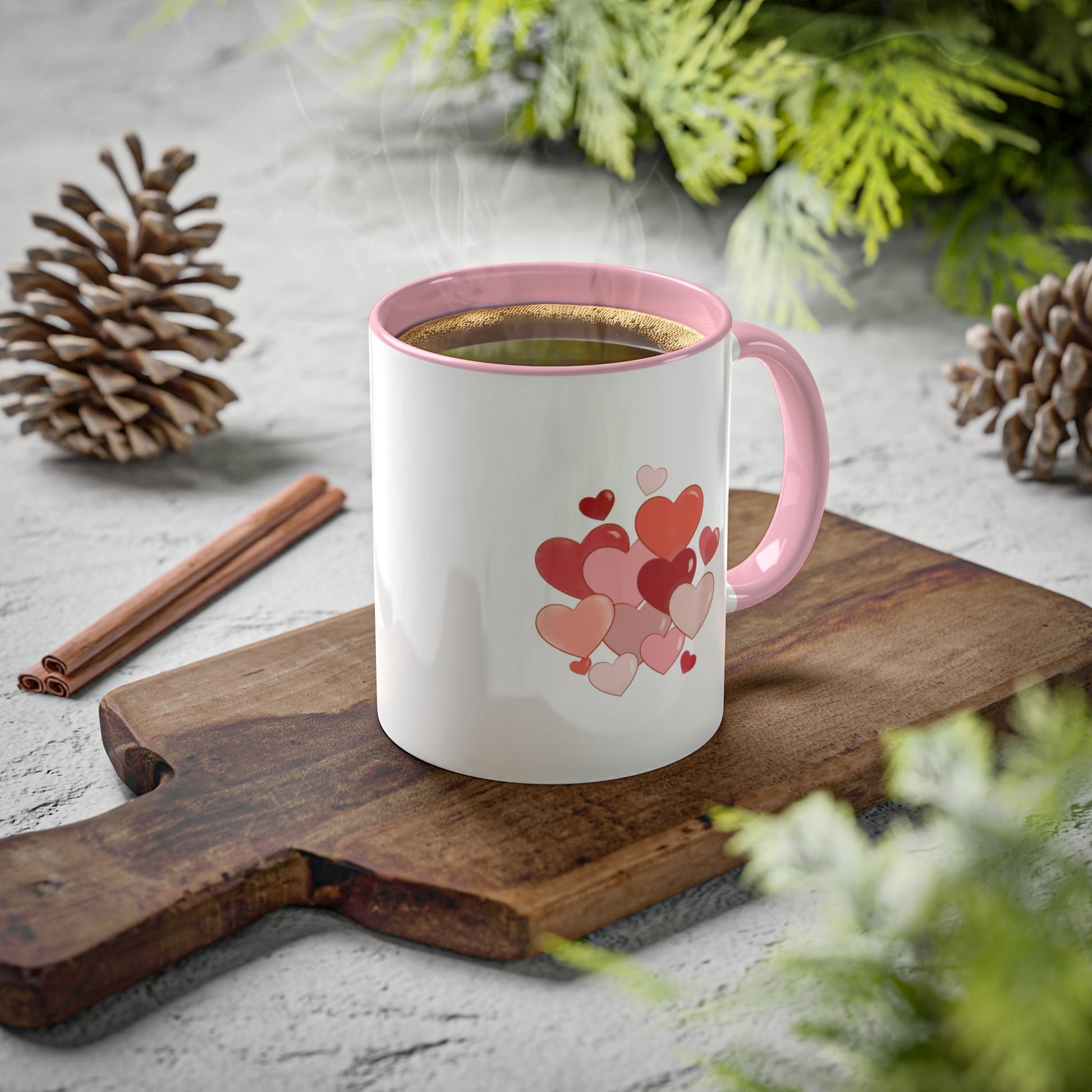 Love Mug MODEL B-V-4 with heart design on a wooden board surrounded by greenery and pinecones.